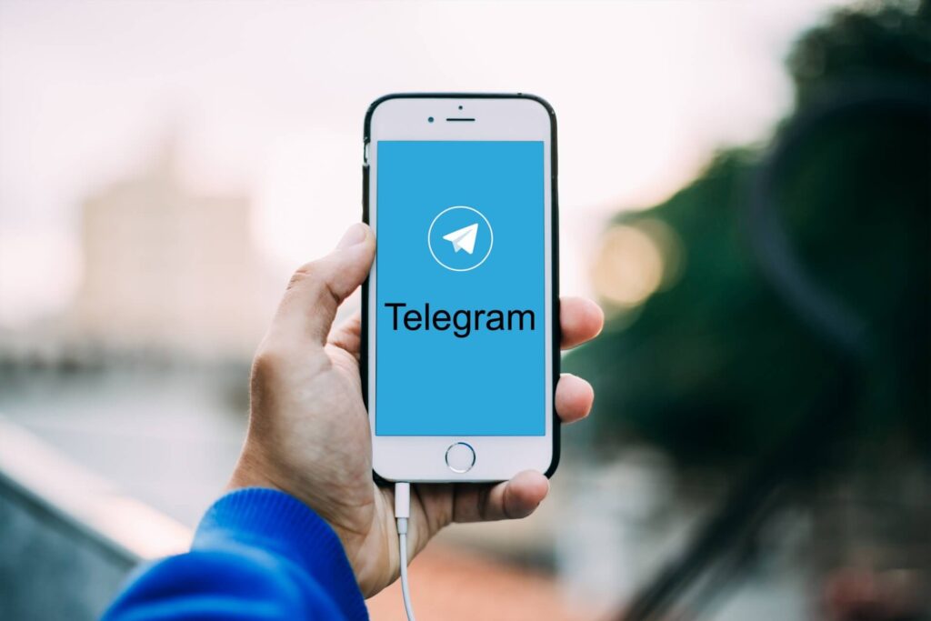 User holding a smartphone with the Telegram app opened.